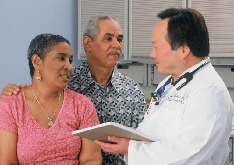 A doctor talking with a patient and her husband as part of a patient-centered care approach.