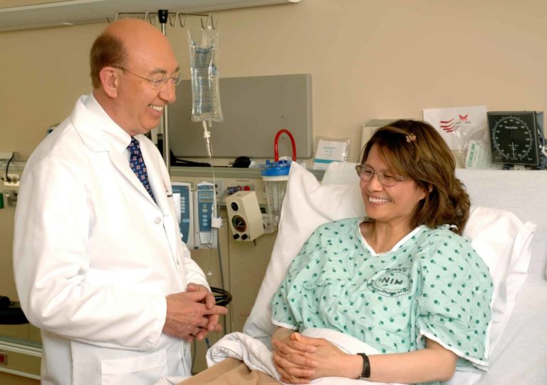 A doctor talking and smiling with a patient in a hospital bed.