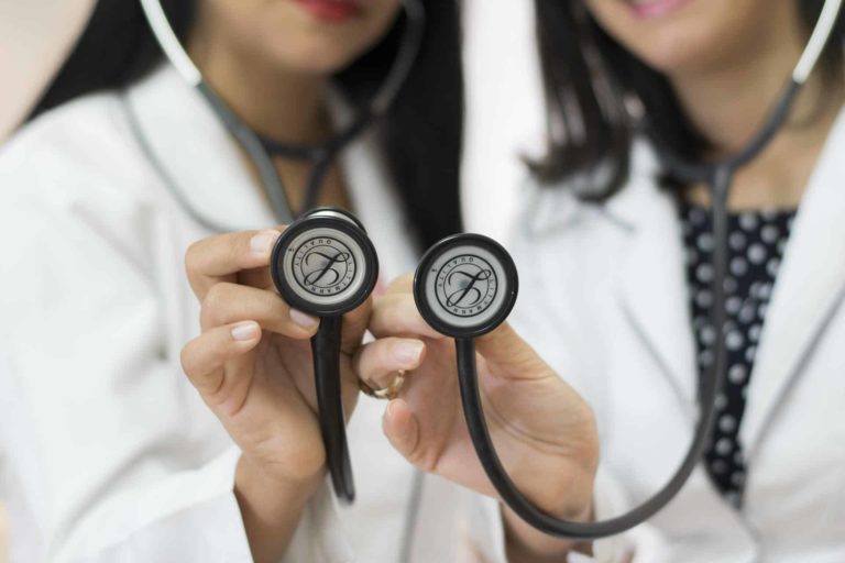two physicians holding up black stethoscopes